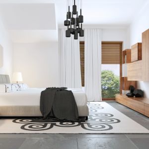 W sypialni, oprócz motywów znanych z pozostałych pomieszczeń, znaleźć można eleganckie czarno-białe elementy na wykładzinie pod łóżkiem. Szyku dodaje też czarny żyrandol. Projekt: ZB5. Fot. Z500