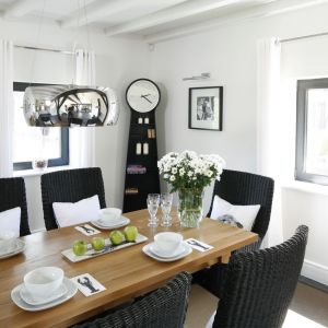 Białe ściany, bawełniane tkaniny, wiklinowe krzesła i drewniany stół wskazują na klimat cottage, który został przełamany nowoczesnymi dodatkami. Fot. Bartosz Jarosz