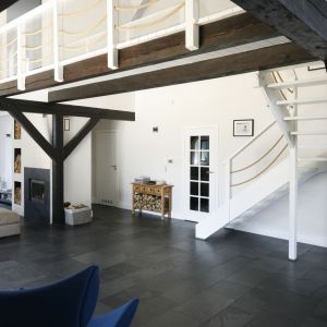 Wewnątrz zachowano stare drewniane belki, które wraz z białymi schodami i sznurowymi barierkami stały się podstawą marynistycznego stylu domu. Fot. Bartosz Jarosz