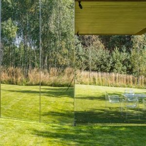 Przestrzeń dzienna przenika się więc rzeczywiście z ogrodem (otwarcie szklanych ścian), jak i iluzorycznie (odbicia w lustrzanych stalowych powierzchniach). Fot. Jakub Certowicz