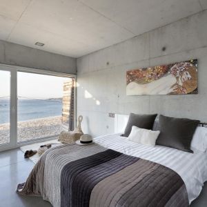 Sypialnia, dość nietypowo, jest betonowym pokojem. Duże wrażenie robi ogromne okno, które umożliwia podziwianie widoków. Fot. Adrián Vázquez
