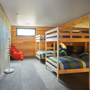 Piętrowe łóżka w sypialni w piwnicy, betonowa ściana i drewniane wykończenie nadają wnętrzu bardzo surowego charakteru. Fot. Ulysse Lemerise Bouchard (YUL Photo)