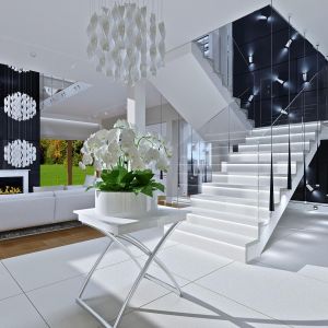 Duże wrażenie robią eleganckie, białe schody prowadzące na piętro. Do nowoczesnego wnętrza idealnie pasują delikatne, szklane balustrady. Fot. MG Projekt