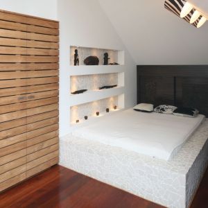 Białe ściany i białe łóżko to główne elementy przestrzeni tej sypialni. Ocieplono ją naturalnym drewnem, z którego wykonana jest szafa. Proj. Katarzyna Mikulska-Sękalska, Fot. Bartosz Jarosz