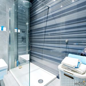 W łazience dominuje szarość z dodatkami turkusu. Całość zaprojektowano estetycznie i funkcjonalnie. Fot. Moti Investment