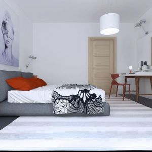 Białą sypialnię ocieplono grafitową podłogą, łóżkiem w tym samym kolorze oraz pomarańczowymi poduszkami. Fot. Z500