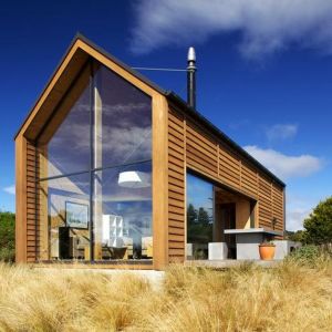 Cała frontowa elewacja tego domu, od strony południowej, jest przeszklona. Dzięki temu zyskuje się "darmową" energię słoneczną. Projekt: Taieri Mouth Crib. Fot. Mason & Wales Architects