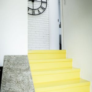 Cegły przemalowano na biało i zielono, a gdzieniegdzie pozostawiono je w wersji oryginalnej. Na klatce schodowej pozostał odkuty beton, a schody z lastryko pomalowano żywicą epoksydową w kolorze żółtym. Fot. APA Innovative
