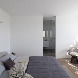 Pokój na piętrze. Biel pomieszczenia podkreślają takie detale jak szara narzuta na łóżko. Fot. Amit Geron 