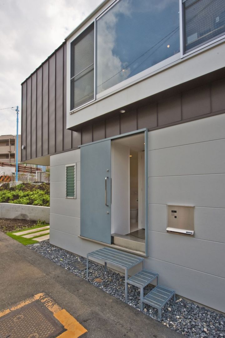 Elewację domu wykończono tak, by wyróżnić część górną. Drzwi wejściowe mają nietypową formę - są przesuwne. Fot. Hiroshi Tanigawa
