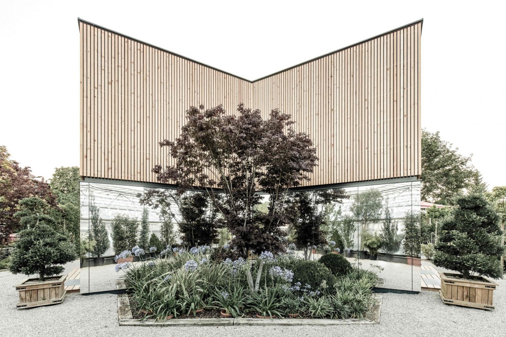 Elewacja domu w połowie pokryta jest specjalnymi lustrzanymi panelami, w której odbijają się otaczające dom krzewy i drzewa, aby podkreślić więź pomiędzy przestrzenią domu, a naturą. Fot. Bernhard Fiedler - JOSEP