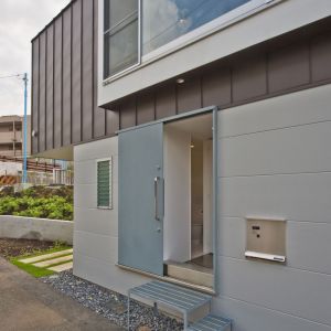 Elewację domu wykończono tak, by wyróżnić część górną. Drzwi wejściowe mają nietypową formę - są przesuwne. Fot. Hiroshi Tanigawa