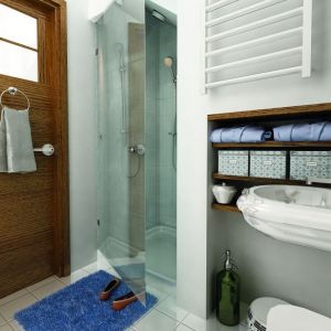 Biała łazienka została zaplanowana bardzo funkcjonalnie. Ocieplono ją drewnem i turkusowymi dodatkami. Fot. Archeco