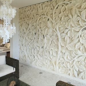 Sprowadzony z Bali ręcznie wykonany relief z piaskowca z motywem kwiatów lotosu zdobi całą ścianę. Grubość reliefu to ok. 20 cm, co daje niesamowite efekty, kiedy go podświetlimy. Projekt: Karolina Łuczyńska, Fot. Bartosz Jarosz
