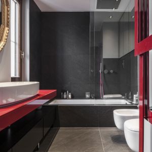 Przy aranżacji pierwszej łazienki, architektka postawiła na  ulubiony kolor klienta – jaskrawą czerwień. Fot. Leonardo Duggento