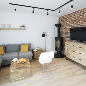 Idealny balans dla surowej cegły na ścianie salonu stanowi drewno w naturalnej odsłonie. Projekt: Katarzyna Uszok-Adamczyk. Fot. Bartosz Jarosz