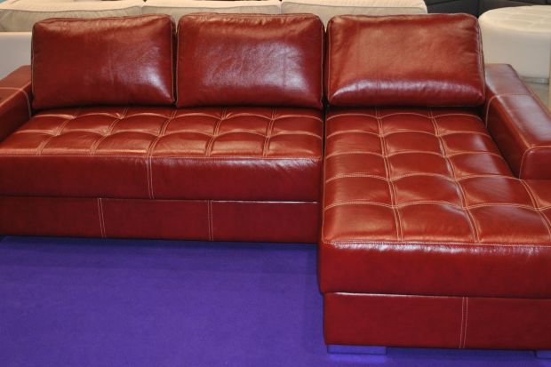 Piękna narożna sofa w obiciu koloru dojrzałej czereśni to idealne opcja na odpoczynek w nowoczesnych wnętrzach, w kt&oacute;rych kr&oacute;lują ciepłe barwy.