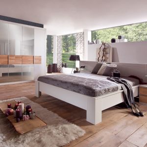 Sypialnia Milano. Białe łóżko pięknie komponuje się z niskimi stolikami nocnymi, wykończonymi okleiną drewnianą. Fot. Telmex