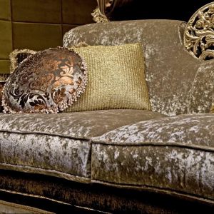 "Margaux" - sofa firmy Exedra prezentuje typowy styl glamour: połyskująca tkanina obiciowa, bogate hafty na poduszkach oraz dekoracyjny element na oparciu mebla. Fot. Exedra. 