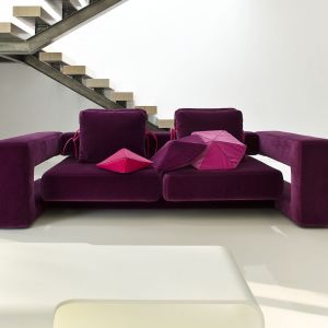 Sofa "Bibik" marki Noti została pokryta tapicerką w nasyconym odcieniu fioletu. Jej obszerne boki zapewniają wygodne podparcie, zaś same siedzisko jest miękkie dzięki poduchom. Fot. Noti