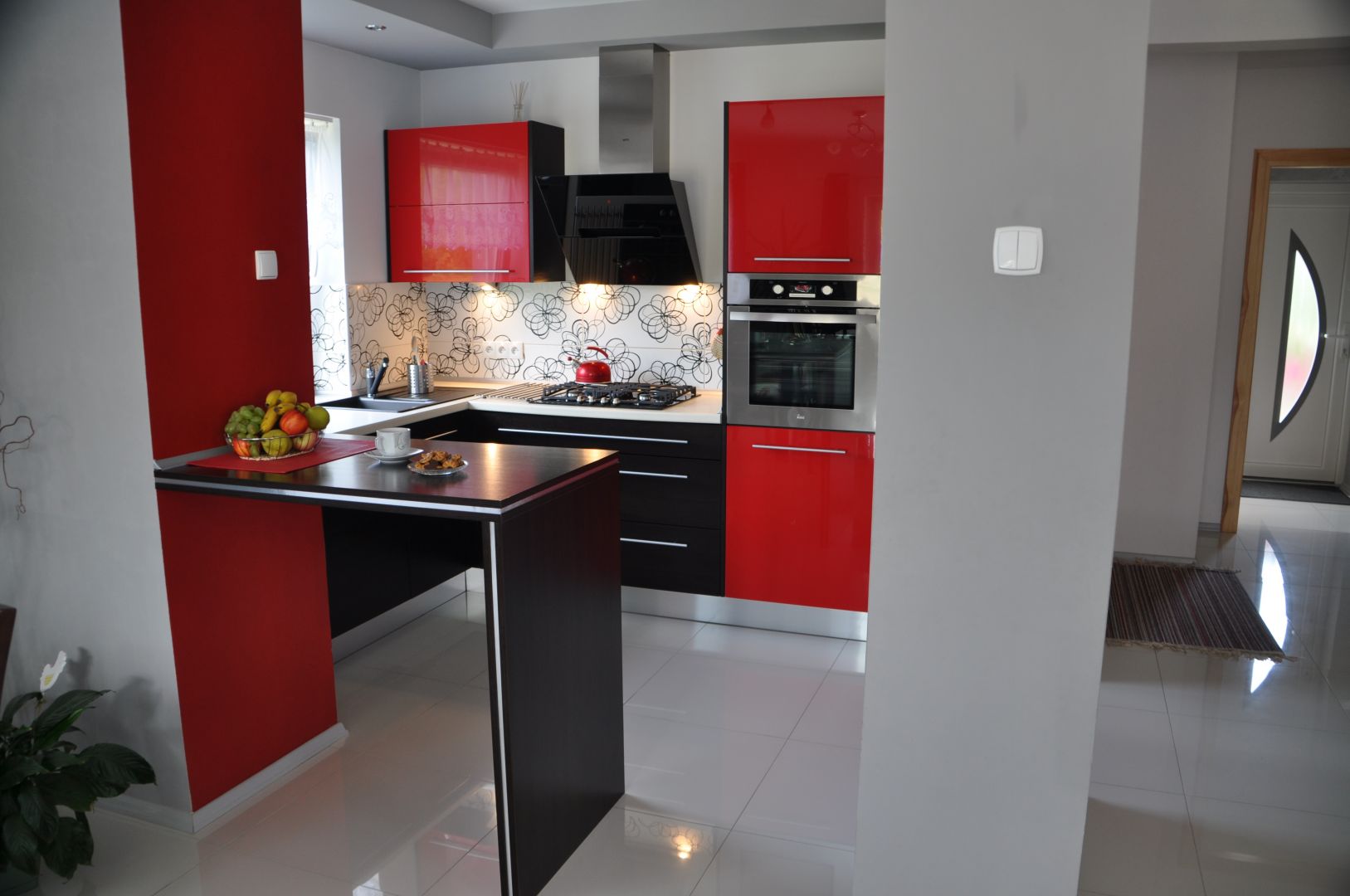 Kuchnia PINIO z czerwonymi meblami, białym blatem i czarnym stołem łączącym kuchnię z salonem
Fot. Kuchnie PINIO