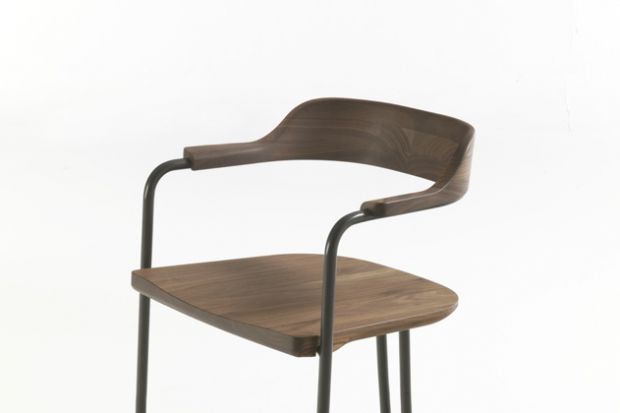 Krzesło "Tubolar" wyr&oacute;żniają zaokrąglone wijące się linie stalowej ramy. Siedzisko, oparcie i podłokietniki wykonane są z litego drewna.