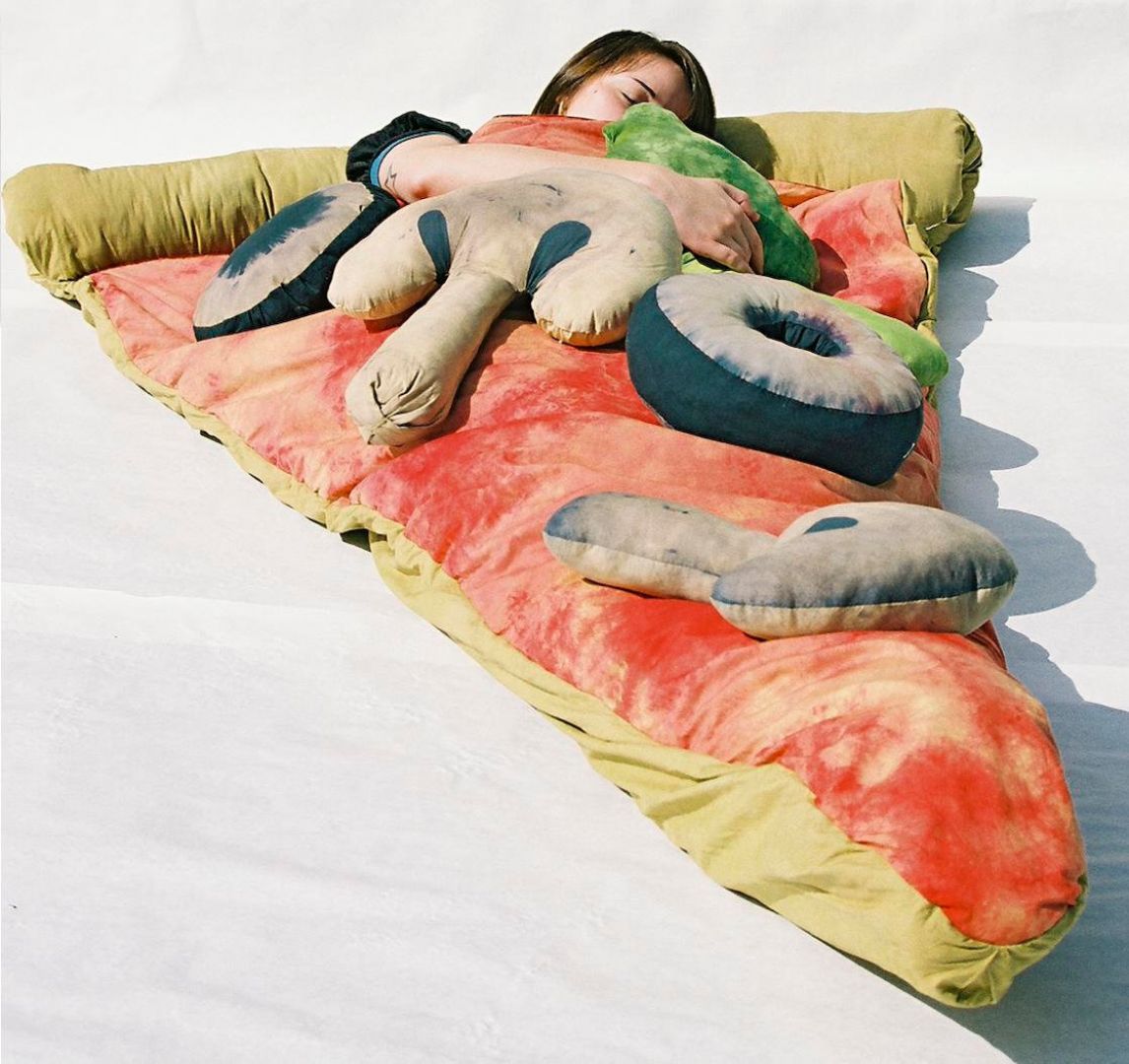 Śpiwór w kształcie pizzy, wykonany z ręcznie barwionej bawełny i wyłożony czerwonym atłasem. 
Fot. Theawesomer