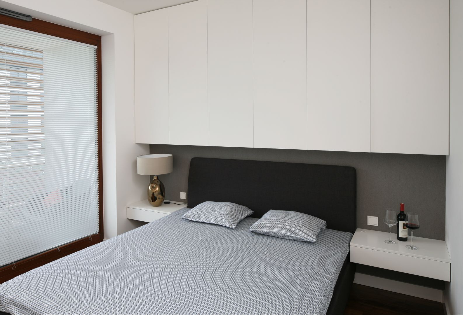 Dzięki wysokim szafkom, umieszczonym nad łóżkiem możemy sprawić, że mała sypialnia będzie wydawała się wyższa. Projekt: Agnieszka Ludwinowska Fot. Bartosz Jarosz 