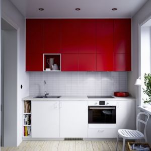 Niewielka kuchnia z energetycznym efektem. Wysoka górna zabudowa w czerwonym kolorze doskonale współgra z bielą, która jest na szafkach dolnych. Fot IKEA