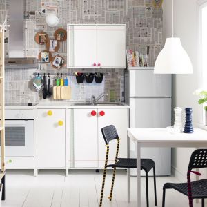 Biała kuchnia z niewielkim, trzyosobowym stołem, który ulokowano tuż pod oknem. Fot. IKEA