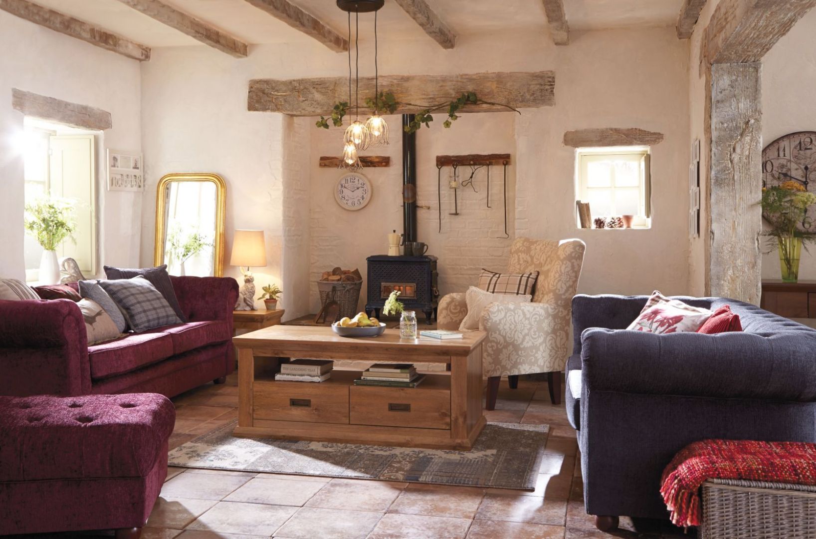 Swojski salon, z dużą ilością naturalnego drewna i sofa w soczystym fioletowym kolorze - nie mogło tu zabraknąć żeliwnej kozy. Fot. Littlewoods Ireland