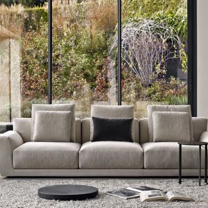 Sofa z dużymi, miękkimi poduchami na oparciu i ciepłym kolorze szarym, lekko wymieszany z beżem. Fot. B&B italia