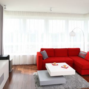 W małym salonie warto zastosować element szczególnie przyciągający uwagę. Może to być soczyście czerwona sofa w otoczeniu bieli. Projekt: Iza Szewc. Fot. Bartosz Jarosz