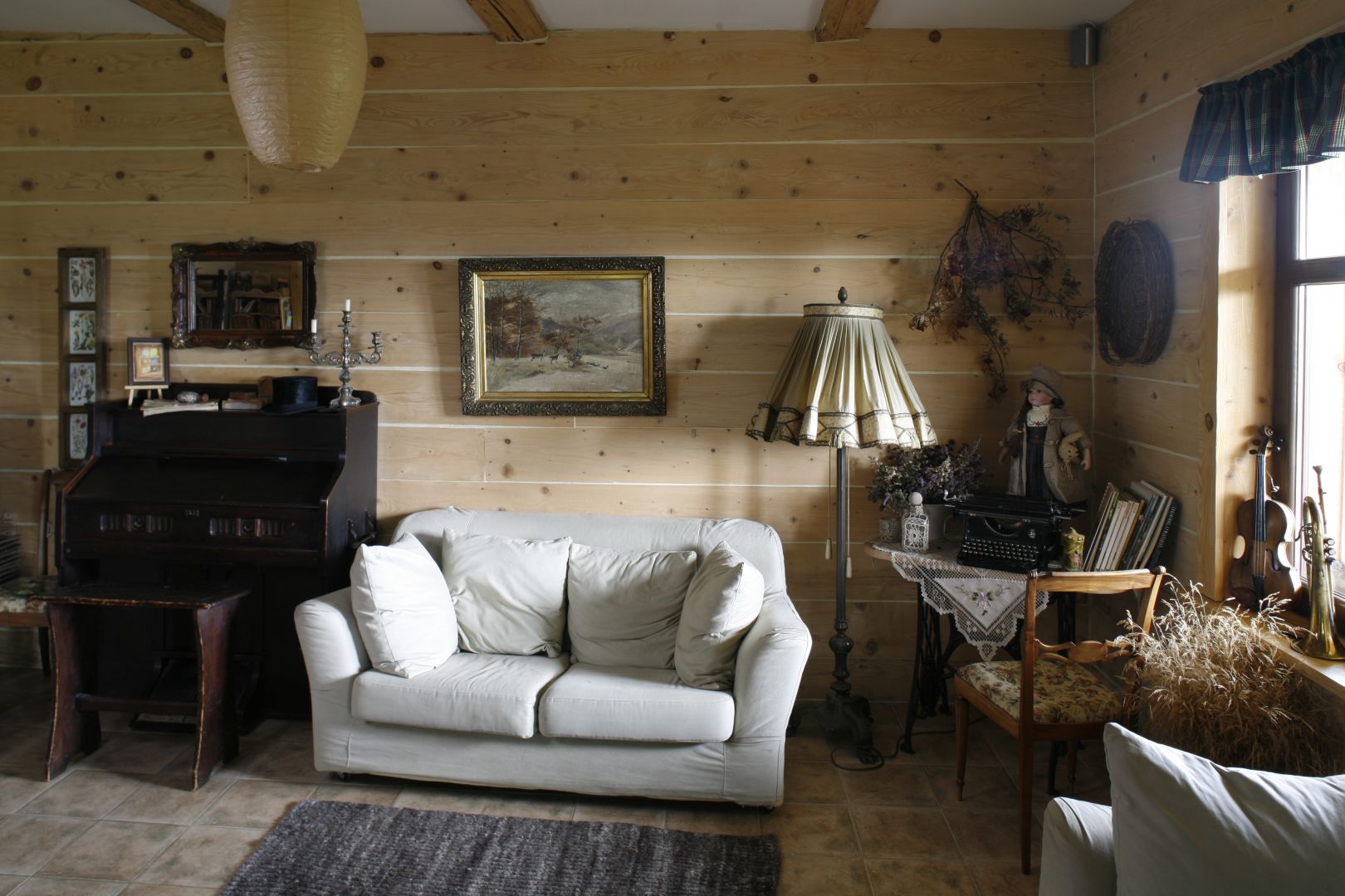 Ten salon to prawdziwe serce domu. Wrażenie przytulności potęgują drewniane ściany ozdobione obrazami w stylizowanych ramach. Projekt: Magda Lutowiska Fot. Bartosz Jarosz
