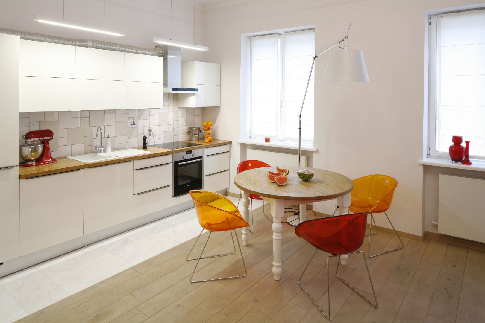 Otwarta kuchnia w białym kolorze jest neutralna dla reszty wnętrza. Aby bardziej ją ożywić, warto przy stole ustawić kolorowe krzesła. Projekt: Agnieszka Żyła Fot. Bartosz Jarosz