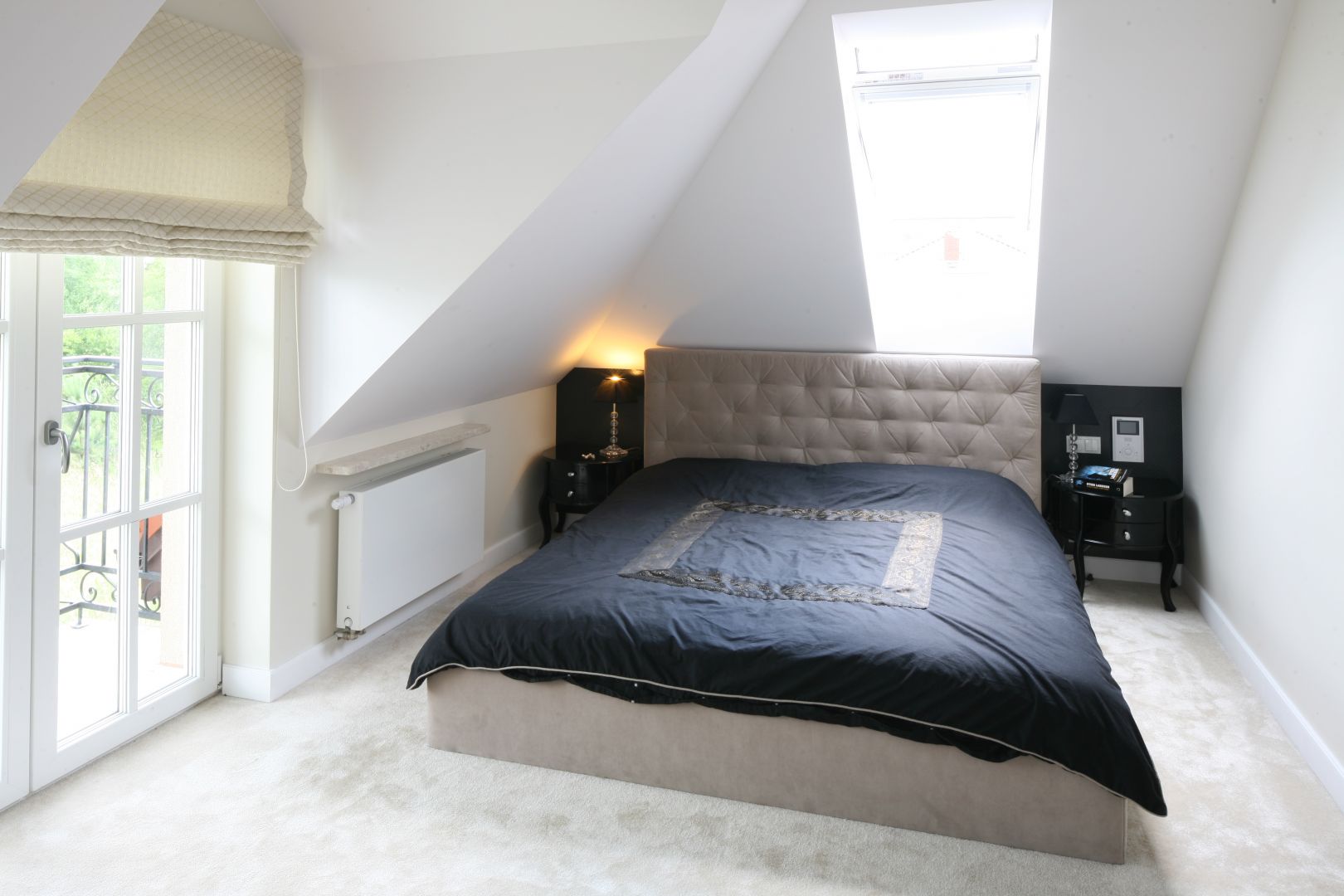 Tapicerowane łóżko z zagłówkiem ociepla białą, minimalistyczną sypialnię. Ciekawym elementem wnętrza są stylizowane stoliki nocne. Projekt: Katarzyna Merta-Korzniakow Fot. Bartosz Jarosz