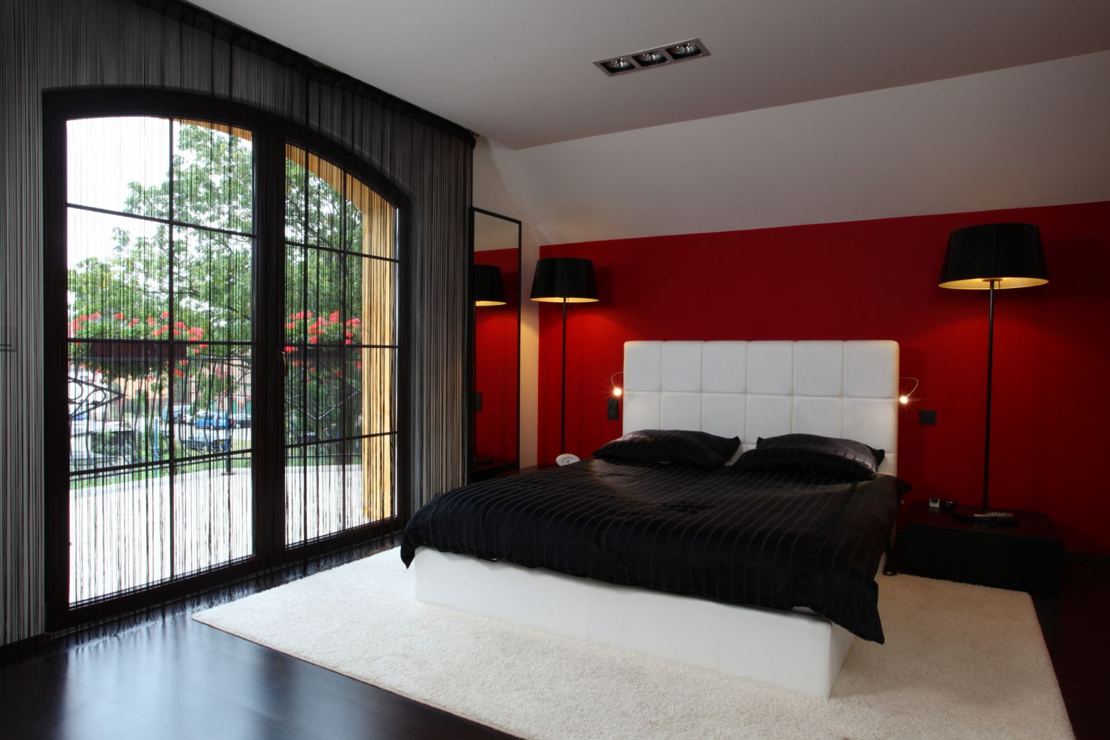 Biały zagłówek łóżka pięknie komponuje się z czerwoną ścianą. Projekt: Anna Kuk-Dutka. Fot. Tomasz Augustyn