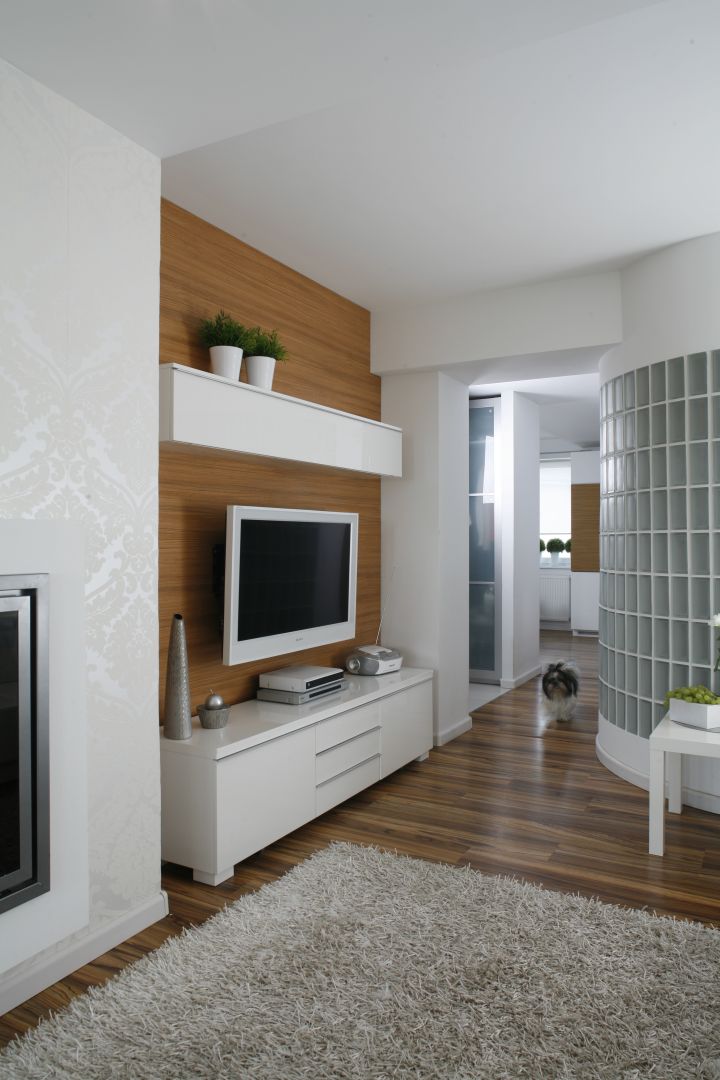 Białe szafki oraz biały odbiornik telewizyjny wyglądają bardzo elegancko na tle ściany wykończonej drewnem. Projekt: Małgorzata Mazur. Fot. Bartosz Jarosz 