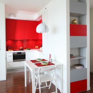 Wnętrze kuchni powiększono poprzez otwarcie jej na pokój, a także przez umiejętnie wykorzystanie kolorów - bieli i czerwieni. Czerwony kolor nadaje małej kuchni głębi, a bały ją rozświetla. Projekt: Iza Szewc. Fot. Bartosz Jarosz 