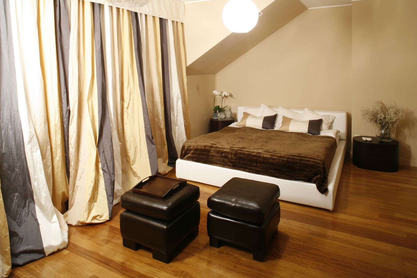 Idealny mariaż beżu oraz bieli. Miękkie, tapicerowane łóżko, zestawiono z brązowymi pufami, na zasadach kontrastu. Projekt: Joanna Liss. Fot. Bartosz Jarosz 