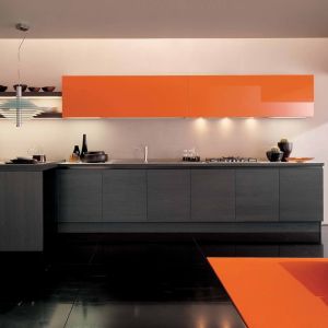 Odważne połączenie szarości z kolorem pomarańczowym w połysku. Kolorowa górna zabudowa ożywia wnętrze. Fot. Euromobil Kitchen