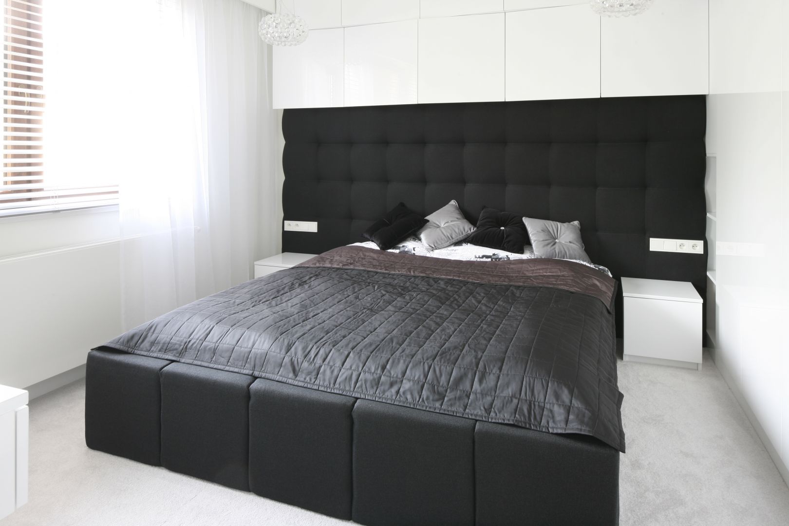 Sypialnia urządzona w czerni i bieli. Piękny dekoracyjny zagłówek rozciągnięty na całą szerokość ściany to ciekawy element wnętrza. Projekt: Dominik Respondek. Fot. Bartosz Jarosz 