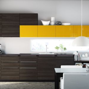 Zabudowa kuchenna choć w ciemnych barwach czekoladowego drewna, jest również bardzo energetyczna. Wszystko za sprawą przełamania brązu soczystym żółtym kolorem. Fot. IKEA