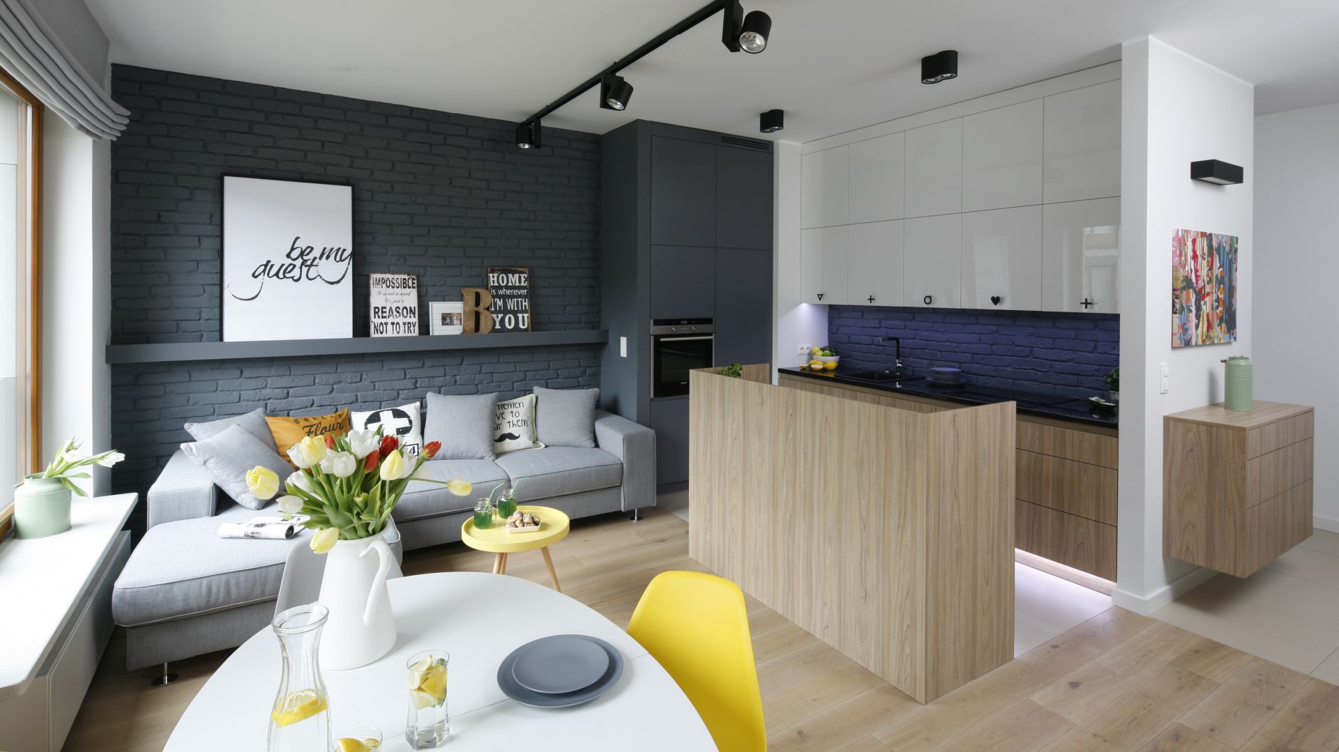 Wnętrze zainspirowane stylistyką loft. Świetnie czują się tutaj zarówno szarości, jak i cegła na ścianie. Pomimo zastosowania w aranżacji ciemnych kolorów na znacznych fragmentach powierzchni ścian oraz wysokiej zabudowy wnętrze pozostało wizualnie jasne i lekkie. Projekt: Ola Kołodziej i Urszula Szmyt. Fot. Bartosz Jarosz
