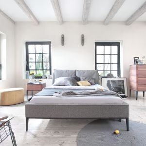 Łóżko Essence ma minimalistyczną formę, ale jest wygodne. Efekt przytulności osiągnięto pokrywając tkaniną większość ramy łóżka i wezgłowie. Fot. Swarzędz Home