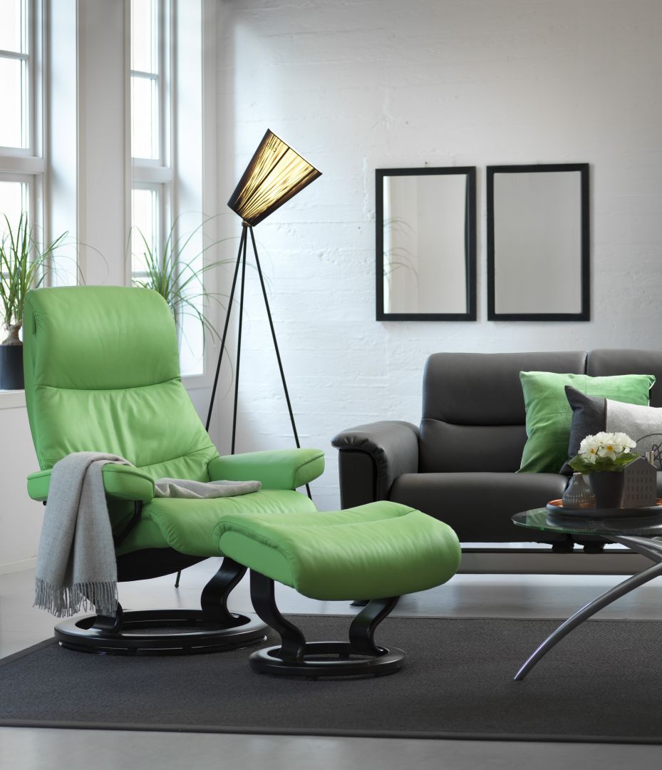 Zielony fotel tapicerowany skórą z podnóżkiem nadaje styl całemu wnętrzu. Zielone poduszki spinają aranżacyjną całość wizualnie. Fot. Ekornes