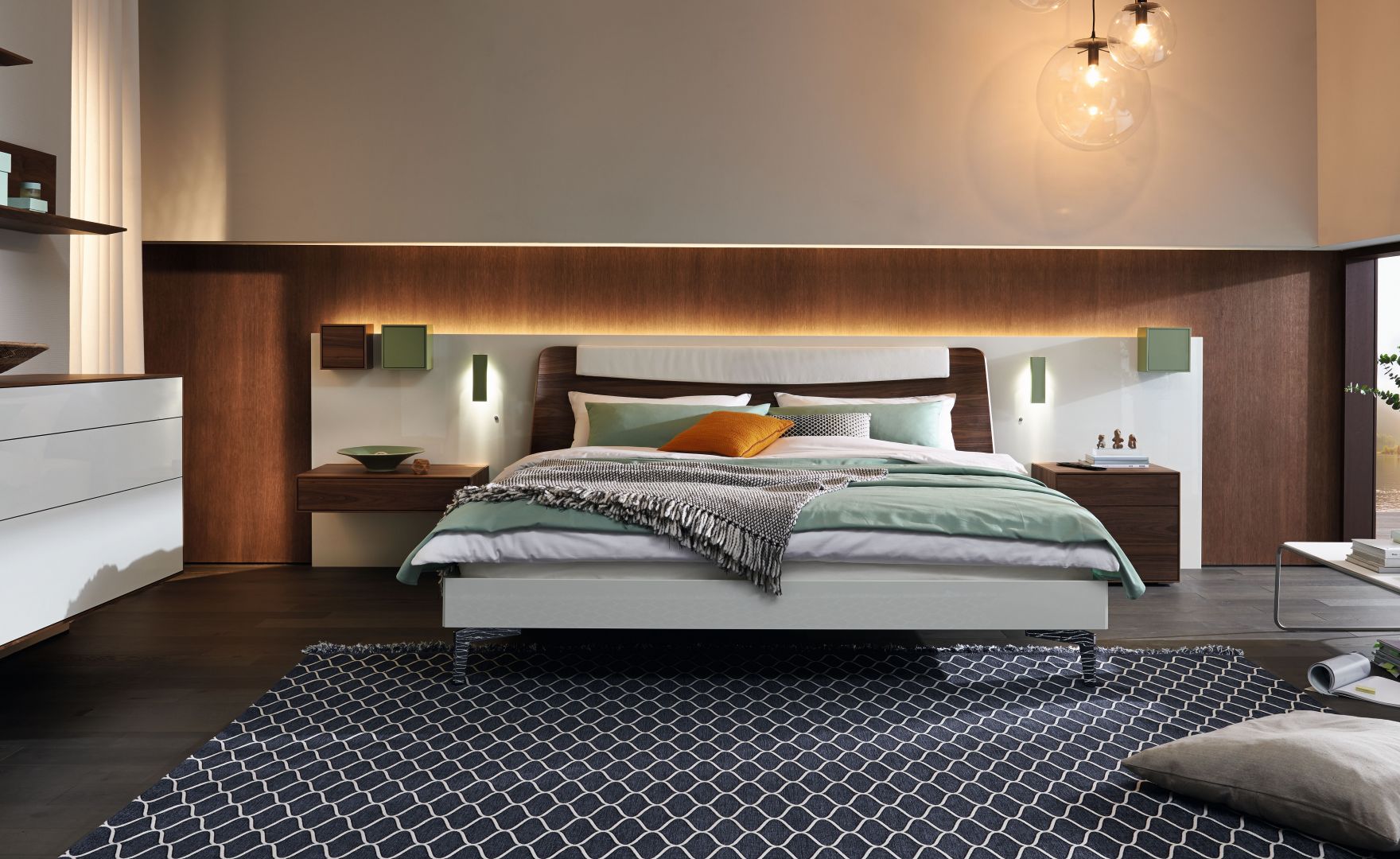 Łóżko firmy Hülsta połączone z panelem ściennym zawierającym półki, stoliki nocne i oświetlenie. Fot. Hülsta