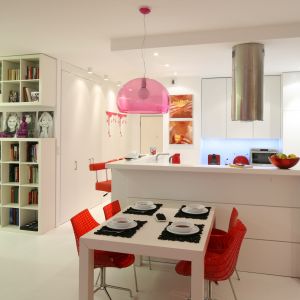 Czerwone krzesła ożywiają biel kuchni połączonej z jadalnią. Projekt Katarzyna Mikulska-Sękalska. Fot. Bartosz Jarosz