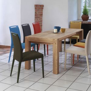 Do prostego drewnianego stołu pasują kolorowe tapicerowane krzesła. Fot. Klose