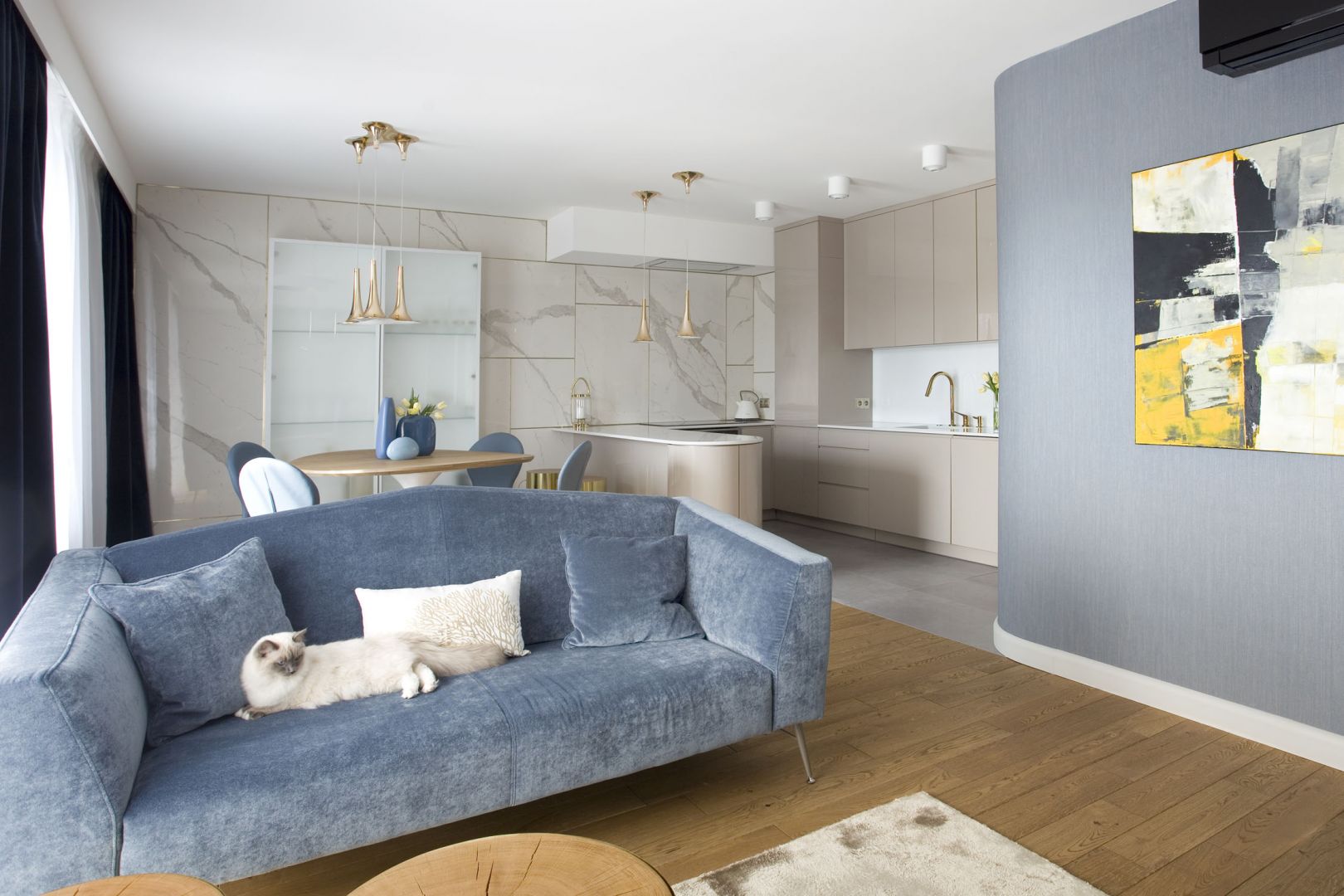 Szaroniebieska sofa pasuje do niewielkiego, przytulnego wnętrza. Projekt: Pracownia Kaza